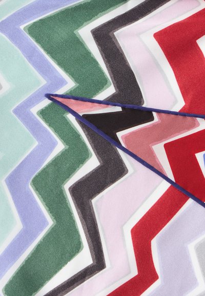 Tissu à motif chevron avec des rayures en zigzag bleues, vertes, noires, roses, rouges et blanches, plié avec une couture bleue visible sur le bord.