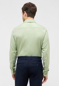 Lange mouwen shirt in lichtgroene stof met een gladde textuur, voorzien van een klassieke kraag en knoopmanchetten, gecombineerd met donkerblauwe broeken.