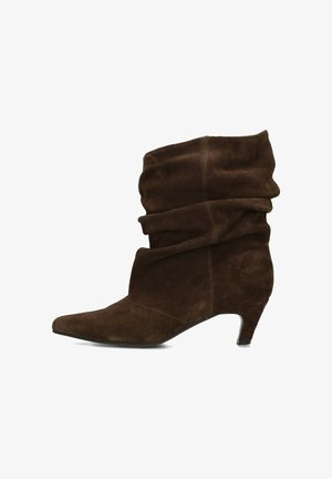 Botte mi-mollet en daim marron à bout pointu et petit talon en forme de chaton, présentée sur un fond blanc.