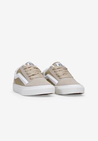 Zapatillas beige con acentos blancos, parte superior de ante y tela, puntera redonda, cordones clásicos, suela plana de goma blanca y emblema en la lengüeta.