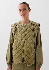 Gevoerde olijfgroene vest met een ronde hals, twee knopen aan de voorkant en brede schouderbanden. Gladde textuur en een ruitenpatroon over het geheel.