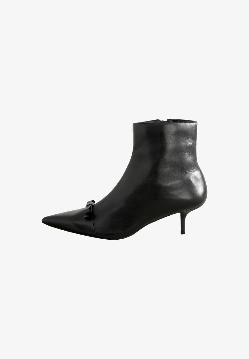 Botte de cheville en cuir noir avec un bout pointu, un talon stiletto bas et un détail de nœud décoratif à l'avant. Texture lisse et design épuré.