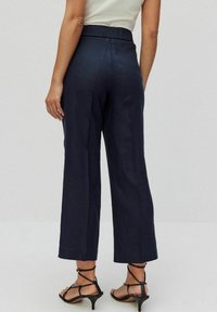 Granatowe lniane spodnie typu wide-leg z wysokim elastycznym pasem, charakteryzujące się gładką teksturą i dopasowanym krojem. Zaprojektowane z luźnym fasonem.