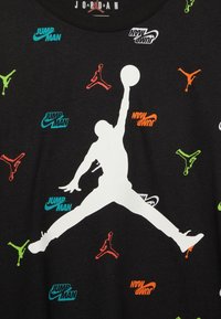 T-shirt nera con una grande silhouette bianca di un giocatore di basket, decorata con loghi Jumpman multicolori in verde, arancione e blu.