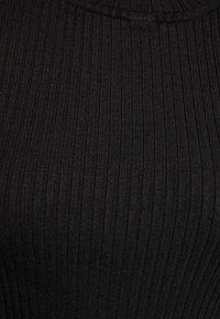 Tissu noir à côtes verticales, avec une texture douce et une coupe près du corps, adapté aux vêtements ajustés.