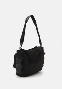 Mala mensageiro de tecido preto com alça ajustável, vários bolsos e costuras reforçadas. Forma retangular com uma textura suave.