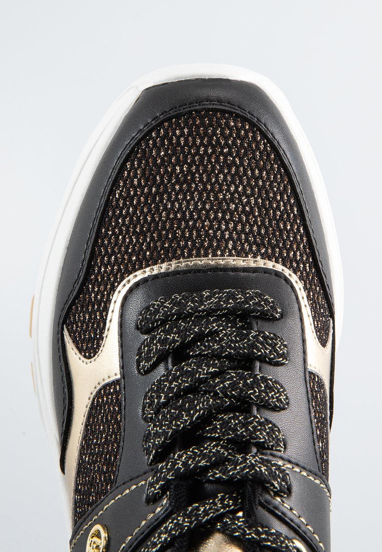 Sneaker nera con una parte superiore in tessuto testurizzato caratterizzata da fili metallici intrecciati. I lacci neri e gli accenti dorati sui lati completano il design.