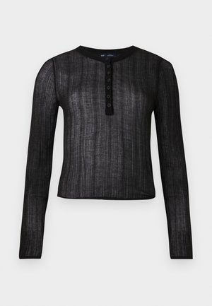 Zwarte top met lange mouwen van semi-doorzichtig materiaal met een ribbelstructuur, voorzien van een ronde halslijn en een knoopsluiting met zes knopen.