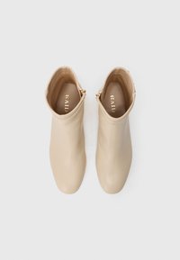 Bottes chelsea beiges en cuir lisse avec une fermeture éclair sur le côté et un bout rond. L'intérieur comprend une semelle intérieure griffée en or.
