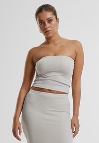 Haut argenté à côtes, sans bretelles, avec une texture lisse, conçu pour épouser les formes. Associé à une jupe crayon ajustée et assortie.