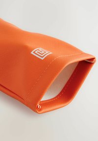 Oranžinė tekstūruota dėklo medžiaga, pagaminta iš patvaraus audinio, su sidabriniu logotipu, siūlėmis ir atviru gale.
