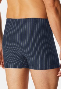Boxer shorts a righe blu navy realizzati in tessuto morbido. Presentano sottili righe verticali azzurre e una vita elasticizzata.
