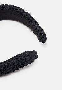Faixa de cabelo tecida em preto com um design de trança texturizada, com um fundo liso e sólido em preto. Forma curvada adequada para vários estilos de cabelo.
