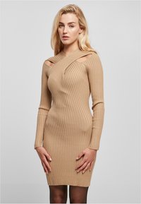 Robe ajustée côtelée en beige clair avec des manches longues, présentant des découpes aux épaules et un design de col torsadé.