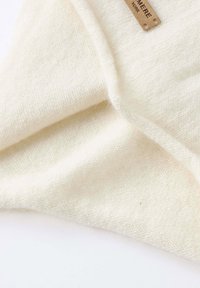 Sciarpa di lana color crema con una superficie morbida e texture. Etichetta cucita nel tessuto, che mette in risalto un design minimalista e una caduta elegante.