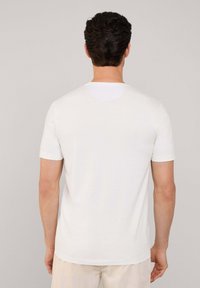 Camiseta de algodón blanca con mangas cortas, cuello redondo y textura suave. Costuras visibles alrededor de las mangas y el dobladillo. Diseño simple y clásico.