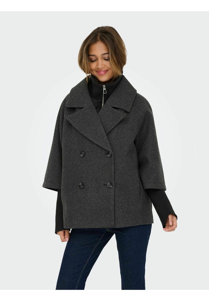 Ciemnoszary płaszcz marynarski z dwurzędowym fasonem, dużym kołnierzem, szerokimi krótkimi rękawami i dwoma guzikami; noszony na czarnym golfie na zamek.