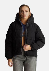 Czarna kurtka puchowa z zapinanym przodem, kapturem i elastycznymi mankietami; ma pikowany wzór i pudełkowy krój.