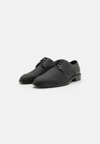 Black formal shoes with a smooth leather finish and a textured toe. Features lace-up design and a low heel.