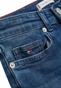 Jeans i mörkblå denim med en klassisk femfickdesign, metalldragkedja och subtil logodetalj i röd, vit och blå på fickan.