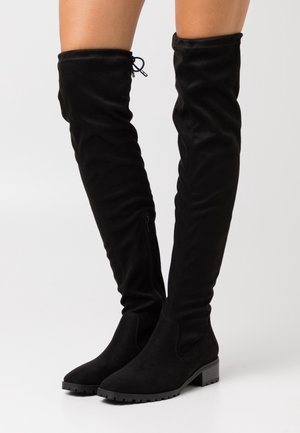 Zwarte boven-de-knie laarzen van zacht suede met een gestructureerde afwerking. Voorzien van een zijrits en een lage blokhak voor stabiliteit.
