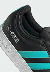 Sorte lædersneakers med turkise striber, tekstureret hvid sål og Mercedes-logo med teksten "AMG PETRONAS Formula One Team".
