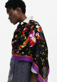 Bufanda floral multicolor con fondo negro, borde púrpura y flores rojas, naranjas y amarillas brillantes en tejido suave.