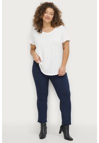 White short-sleeve t-shirt with a scoop neckline paired with navy fitted pants and black ankle boots. Simple, breathable design.