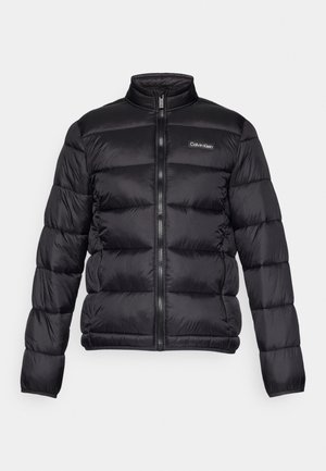 Fekete puffermellény magas gallérral, cipzáros elülső résszel és varrott rekeszekkel. A bal mellen egy kis Calvin Klein logó található.