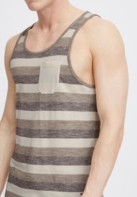 Stribet tanktop i beige og brun, lavet af blød bomuld, med en lomme foran og brede ærmehuller for en afslappet pasform.