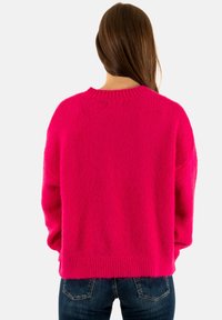 Maglione oversized fucsia con finitura texturizzata, colletto e polsini a costine, caratterizzato da una vestibilità rilassata e spalle scese.