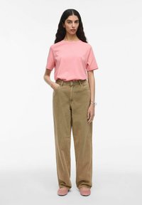 T-shirt in cotone rosa chiaro, vestibilità comoda; pantaloni beige a vita alta e larghi; scarpe slip-on rosa morbido; texture liscia, design semplice.