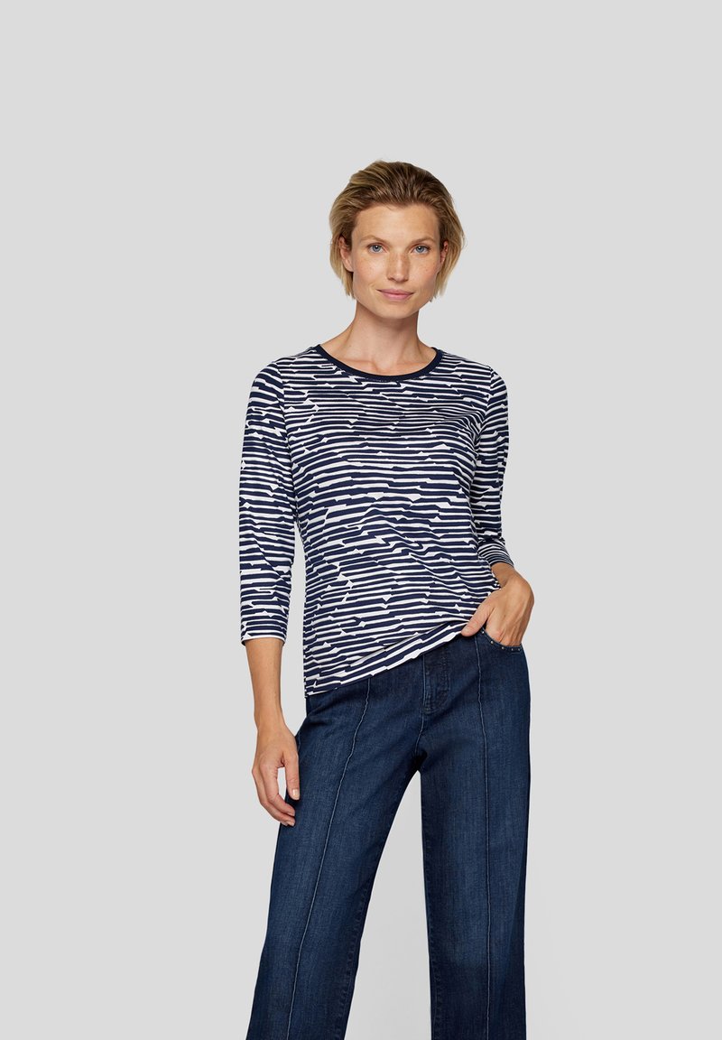 Marineblau-weiß gestreiftes Langarmoberteil mit rundem Halsausschnitt und lockerer Passform, kombiniert mit geraden Jeans in dunkler Denim-Optik.