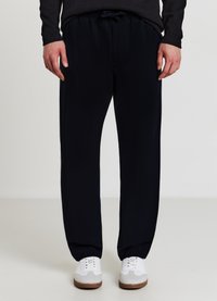 Marineblaue Jogginghosen aus weichem Stoff, mit einem elastischen Bund und Kordelzug, Seitentaschen und zulaufenden Beinen.