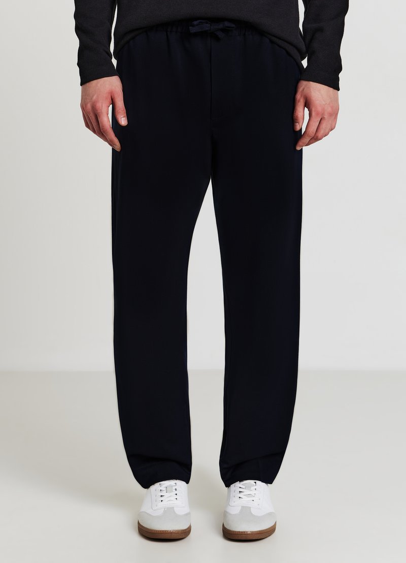 Marineblaue Jogginghosen aus weichem Stoff, mit einem elastischen Bund und Kordelzug, Seitentaschen und zulaufenden Beinen.