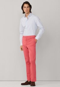 Lichtblauw-wit gestreept shirt met lange mouwen, gecombineerd met effen roze broek. Bruine schoenen, klassiek ontwerp, nauwsluitende stijl.