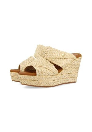 Sandalias de cuña con parte superior trenzada similar a paja en color beige. Presentan un diseño de tiras cruzadas y una suela de plataforma apilada, acentuada con un logo dorado.