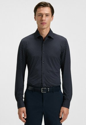 Navyblaues Langarmshirt mit einem subtilen weißen Punktmuster, ausgestattet mit einem Button-Down-Kragen und einem taillierten Design.