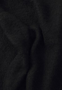 Mustrine tekstuuriga must kangas, millel on pehme ja karvane välimus, näidates voldid ja kortse. Materjal näeb välja tihe ja soe.