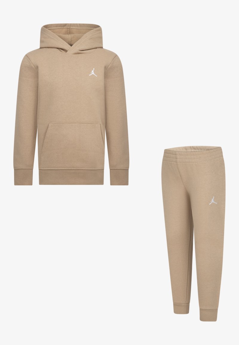 Sweatshirt capuche beige avec poche frontale et logo blanc ; assorti avec un pantalon de jogging fuselé. Les deux sont en tissu doux et texturé.