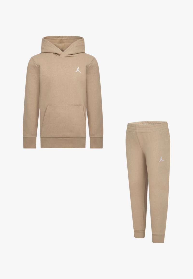 Tan hooded sweatshirt with front pocket and white logo; paired with matching tapered sweatpants. Both made of soft, textured fabric.
