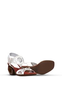 Sandales à talons en cuir blanc avec des motifs floraux découpés, semelle intérieure en suède rouge et un talon angulé unique. Semelle texturée pour une meilleure adhérence.