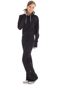 Black zip-up hoodie with high collar, ribbed cuffs, drawstrings; paired with black wide-leg pants and light gray athletic shoes.
