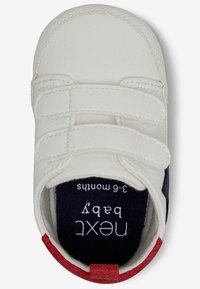 Scarpina bianca per bambini con cinturini in velcro e dettagli blu navy e rossi. Parte superiore in vera pelle, punta tonda e foderato interno etichettato "next baby". Taglia 3-6 mesi.