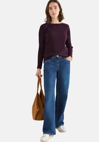 Ribbad mörk lila långärmad tröja, högmidjade blå utsvängda jeans och vita sneakers. Brun mockaväsk med axelremmar.