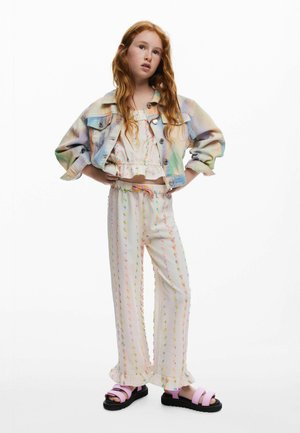 Jachetă ușoară din denim cu gradient pastel, top alb cu volane și pantaloni cu model de puncte colorate. Sandale roz cu tălpi negre.