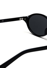 Černé kulaté sluneční brýle s tmavými skly. Rámeček je lesklý, vyrobený z plastu, s kovovým akcentem na pantě.