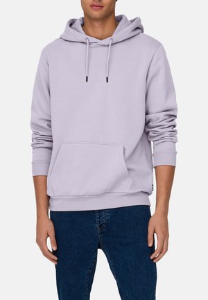 Sudadera de algodón de color púrpura claro con un bolsillo canguro, capucha ajustable con cordón y puños de canalé, llevada sobre unos jeans azul oscuro.