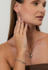 Silver star pendant necklace, matching star bracelet, and hoop earrings with a crystal accent. Smooth metal surface and polished finish.
