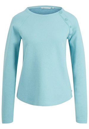 Light blue long-sleeve top with a rounded neckline, raglan sleeves, and button accents on one shoulder. Made from a soft, textured fabric.